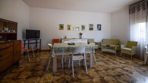 A living room with a dining table, chairs, a television, and artwork on the wall. - Amazing home in Ispica with WiFi (Ispica)