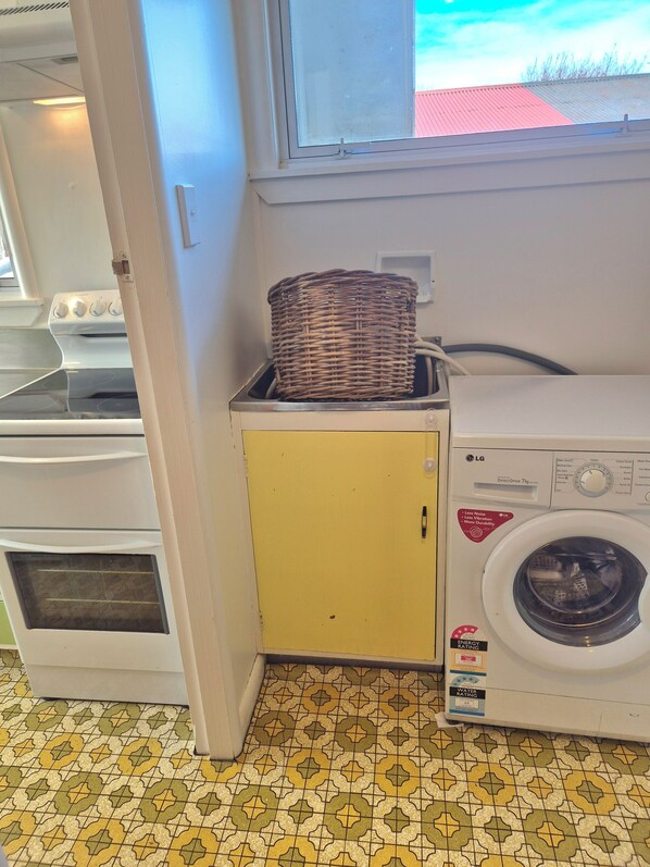 Un espace buanderie comprenant un lave-linge, un sèche-linge et un petit meuble de rangement.