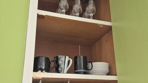 A kitchen cabinet with shelves holding various kitchenware items. - Tāhunanui Nest (Nelson)