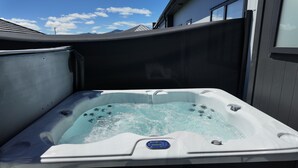 Een hottub met een digitaal bedieningspaneel, omgeven door een metalen kuip, met een heldere lucht op de achtergrond.