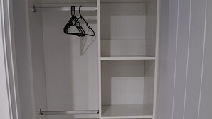 A walk-in closet with open shelves and a hanging rod.