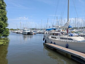 Ein Yachthafen mit mehreren angestückten Booten, ruhigem Wasser und wolkenlosem Himmel.