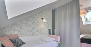 Ein Schlafzimmer mit einem Bett, einem Kopfteil, einer Wandleuchte und einem Fenster mit Vorhängen.