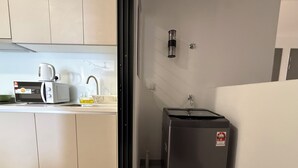Una cocina compacta con microondas, tostadora, lavabo y un refrigerador pequeño.