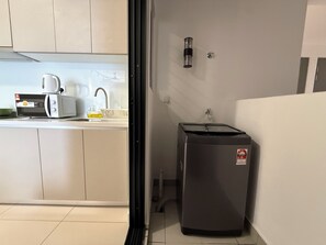Une cuisine compacte équipée d’un four à micro-ondes, d’un grille-pain, d’un évier et d’un petit réfrigérateur.