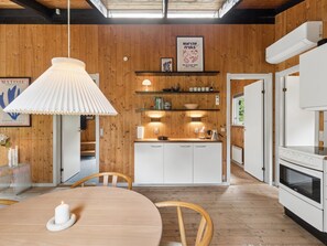 A modern kitchen with wooden walls, white cabinetry, and a central island. There is a pendant light above the island and a framed picture on the wall. - "Erich" - 500m from the sea by Interhome (Aakirkeby)