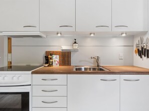 Une cuisine moderne avec des meubles blancs, un plan de travail en bois et un évier en acier inoxydable.