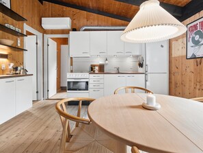 Une cuisine moderne avec des meubles blancs, une cuisinière et un coin repas comprenant une table et des chaises en bois.
