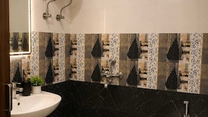 Un baño con lavamanos pedestal blanco, inodoro, ducha y calentador mural.