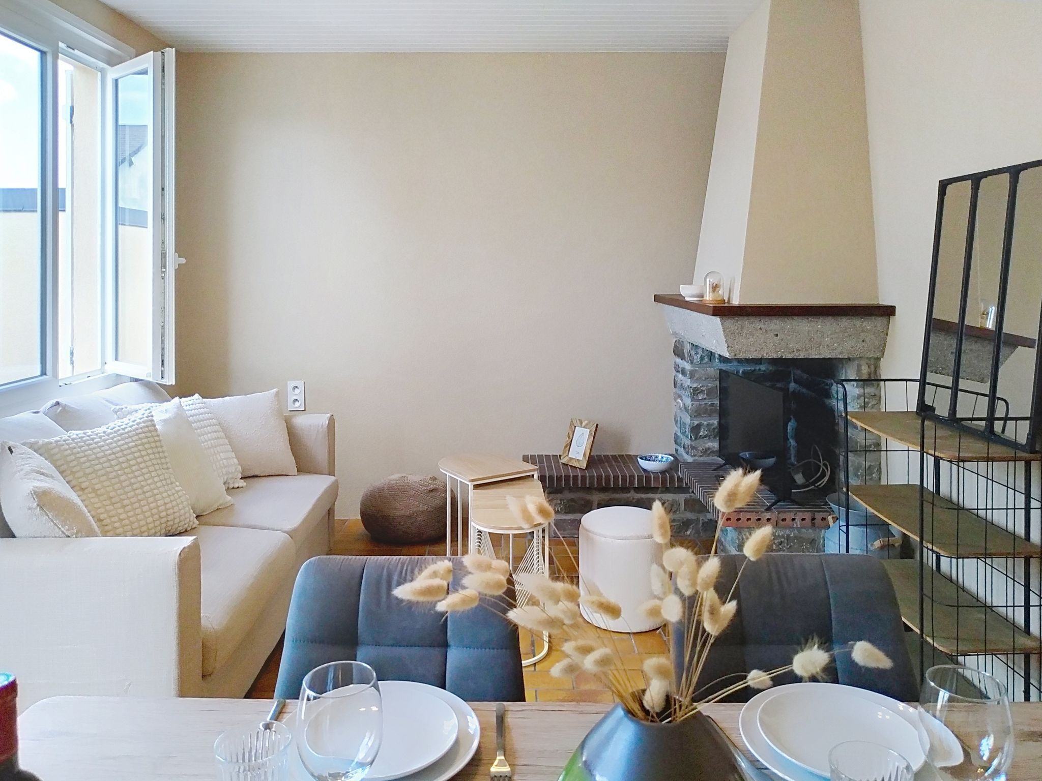 Un salon avec un canapé, une table à manger dressée avec des assiettes et des verres, une cheminée et un escalier.