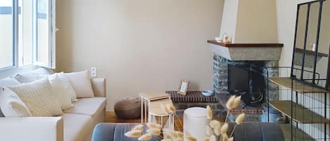 Una sala de estar con un sofá, una mesa de comedor dispuesta con platos y vasos, una chimenea y una escalera.