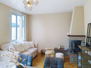 Uma sala de estar com sofá, mesa de centro, lareira e uma grande janela.