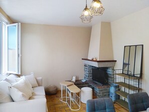A living room with a fireplace, a sofa, a coffee table, and a chair. - Riviera by Interhome (Agon-Coutainville)