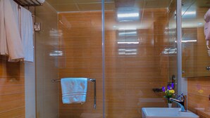 Een moderne badkamer met een douche in glazen cabine, een wastafel met spiegel en een handdoekrek.