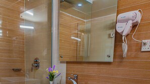 Een moderne badkamer met een grote spiegel, een witte wastafel, een haardroger en toiletartikelen op het aanrecht.