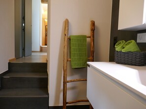 Eine Treppe führt zu einem Raum mit einer Holzleiter und einem grünen Handtuch, das daran hängt.