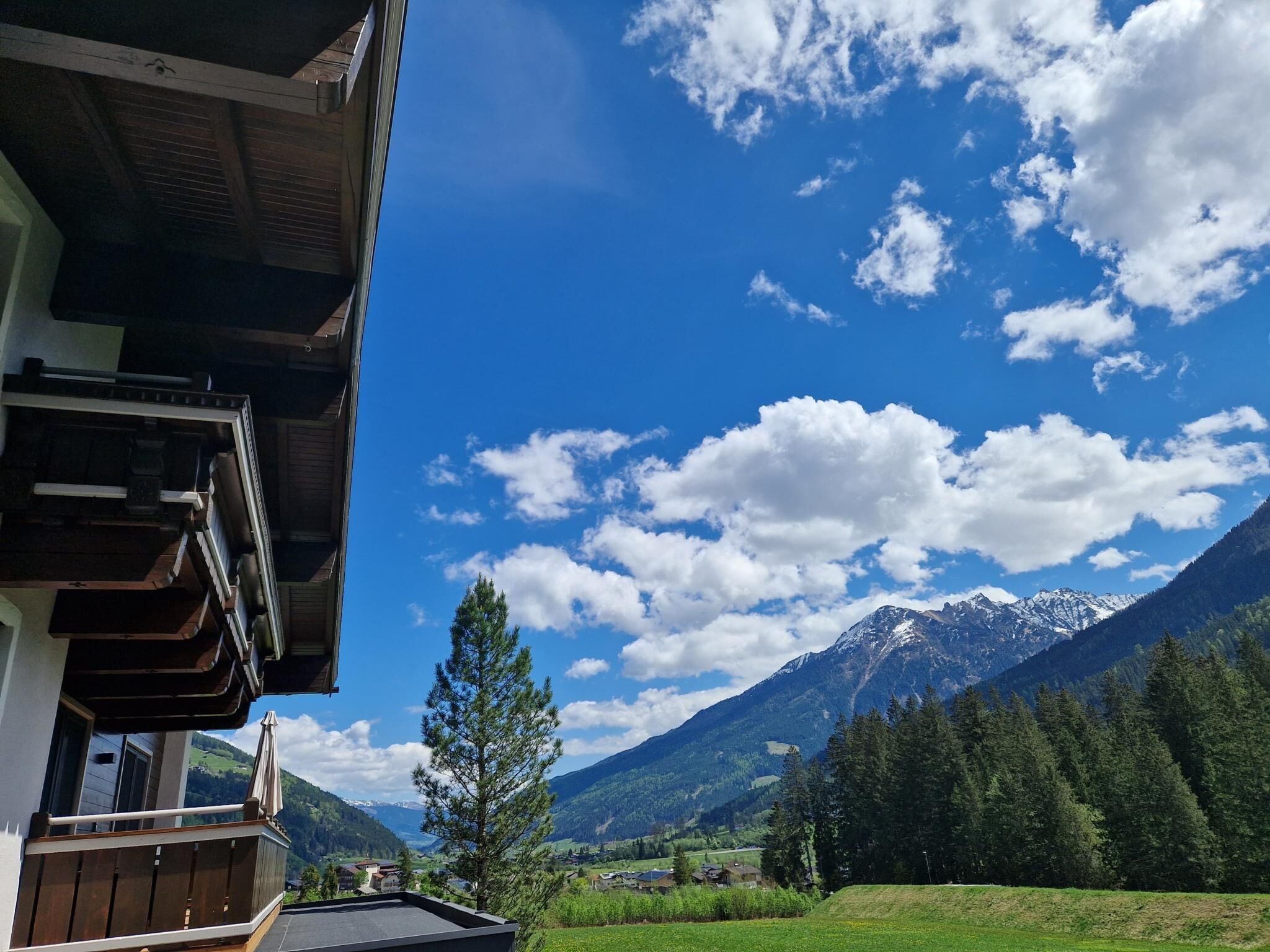 A mountain landscape with a clear sky and a building with a balcony overlooking the view.