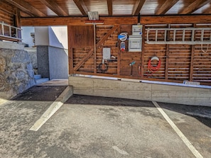 A covered outdoor area with a wooden floor, a stone wall, and various electrical equipment. - Spacious living with alpine charm and balcony (Neukirchen am Großvenediger)
