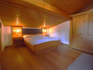 A single wooden bed in a room with a sloped ceiling and wooden walls. - Charming and comfortable apartment (Wald im Pinzgau)