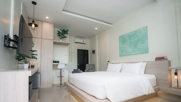 A modern bedroom with a bed, bedside table, and a desk area with a chair.