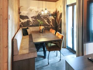 Un'area pranzo con tavolo in legno, sedute su panche imbottite e un murale decorativo.