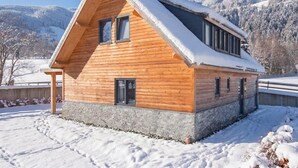 Eine Holzhütte mit geneigtem Dach, Stein Fundament und mehreren Fenstern.