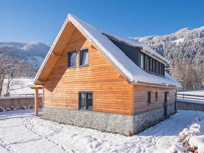 Una baita in legno con tetto spiovente, fondamenta in pietra e diverse finestre.