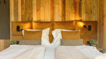 A double bed with white linens, two pillows, and a wooden headboard with wall-mounted lights.