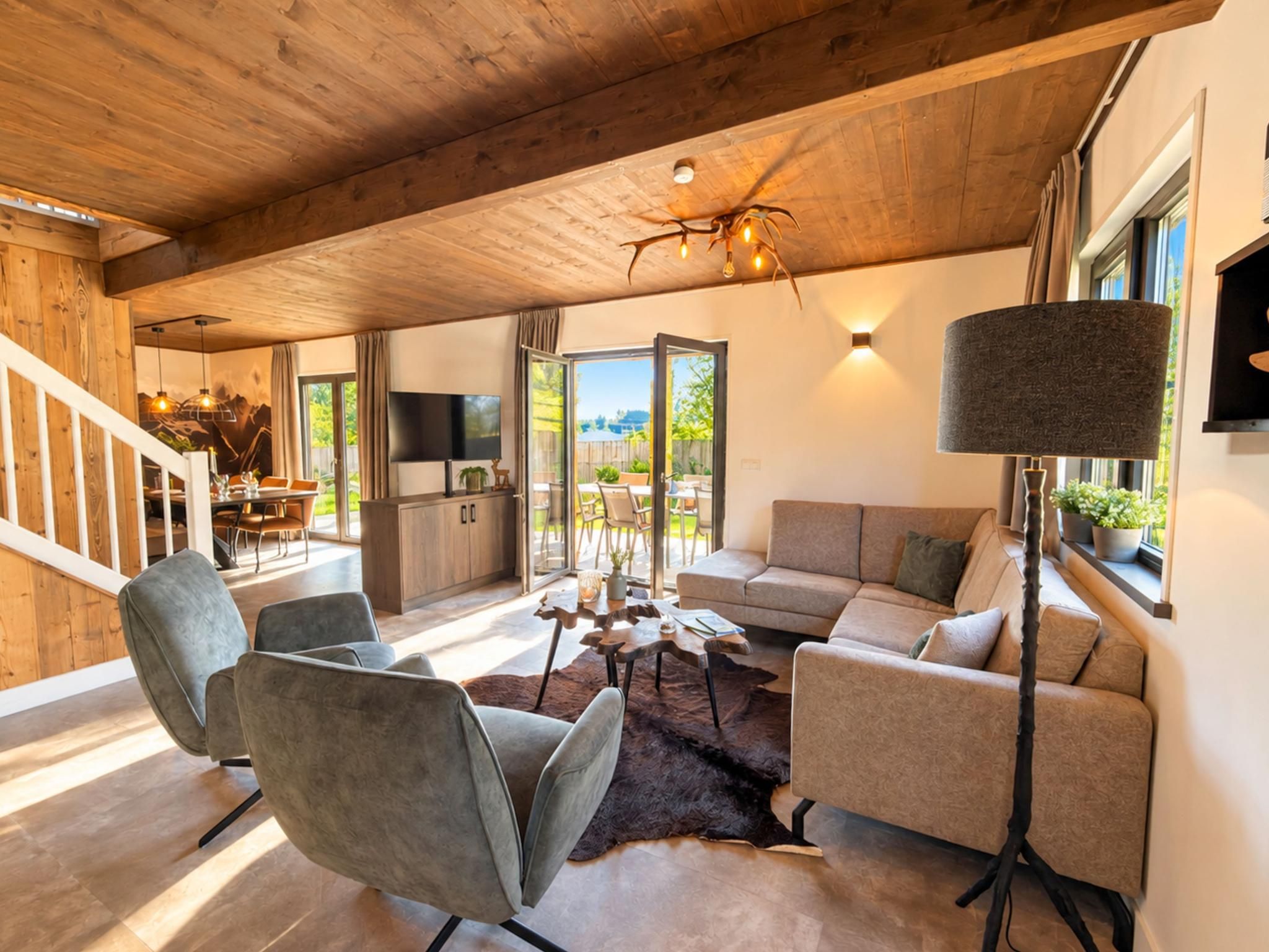 A spacious living area with a wooden ceiling, a modern sofa set, a coffee table, and a television.