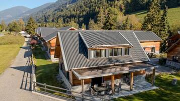 A row of modern cabins with sloped roofs, a covered outdoor seating area, and a gravel driveway.