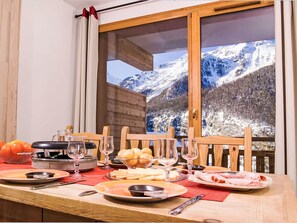 A dining table with a view of snow-covered mountains through a large window. - Les Balcons des Airelles by Interhome (Les Orres)