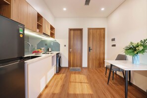 A compact kitchen with a refrigerator, sink, and wooden cabinets. - VENTURA by BRIO (Da Nang)
