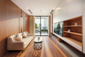 A modern living room with a sofa, a coffee table, and a TV on a wooden shelf. - VENTURA by BRIO (Da Nang)