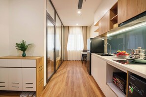 Una cocina moderna con armarios de madera, un refrigerador, un lavamanos y un comedor con una mesa y sillas.
