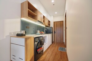 Una cocina compacta con muebles de madera, lavadora incorporada y microondas.