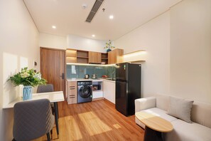 Un espacio habitable compacto con kitchenette, lavadora, sofá y zona de comedor.