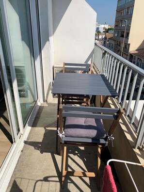 A balcony with a table and chairs, a white railing, and a view of buildings. - Studio for rent, 100 meters from the beach in Palavas-les-Flots. (Palavas-les-Flots)