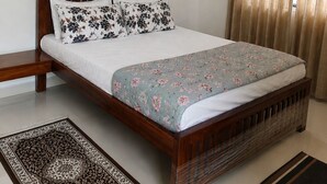 Ein Schlafzimmer mit Bett, Nachttisch, einem Gemälde und einem Fenster mit Vorhängen.