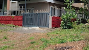 Ein modernes, zweistöckiges Haus mit Flachdach, einem verschlossenen Eingangsbereich und einem kleinen Garten.