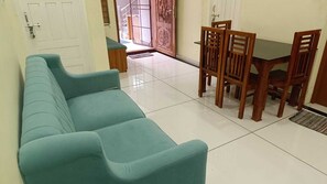 Un salón con un sofá color turquesa, una mesa de comedor de madera y sillas.