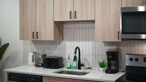 Een keuken met houten kastjes, een magnetron, een koffiezetapparaat, een broodrooster en een vaatwasser.