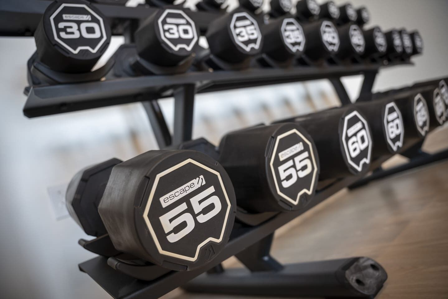 A rack of dumbbells with varying weights, labeled with numbers and the brand 'Escape.'