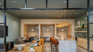 Een modern interieur met een bar, zitgedeelte en een keuken die zichtbaar is door glazen scheidingswanden.