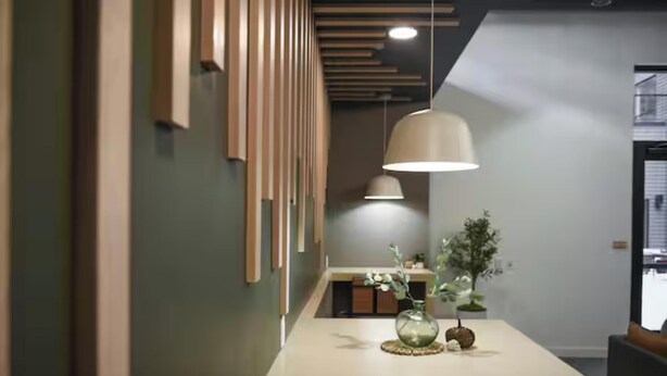 Een modern interieur met een lange gang, hanglampen en een tafel met een vaas en plant.