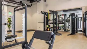 Een fitnessruimte met trainingsapparatuur, een spiegel en een bank.