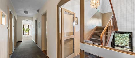 A hotel corridor with a view of a staircase and a door labeled 'Drucken'.