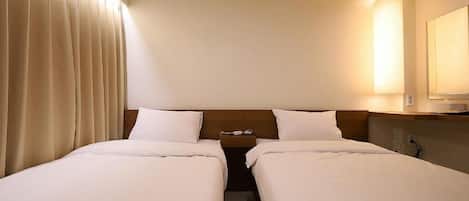 Habitación de hotel con dos camas, una mesita de noche, una lámpara y un espejo.