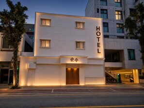 A modern hotel building with a prominent 'HOTEL' sign, a covered entrance, and a staircase leading to an upper level. - Sunsu Hotel Mia (Seoul)