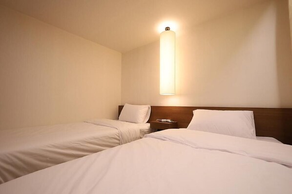 A hotel room with two single beds, a nightstand, and a wall-mounted light fixture. - Sunsu Hotel Mia (Seoul)