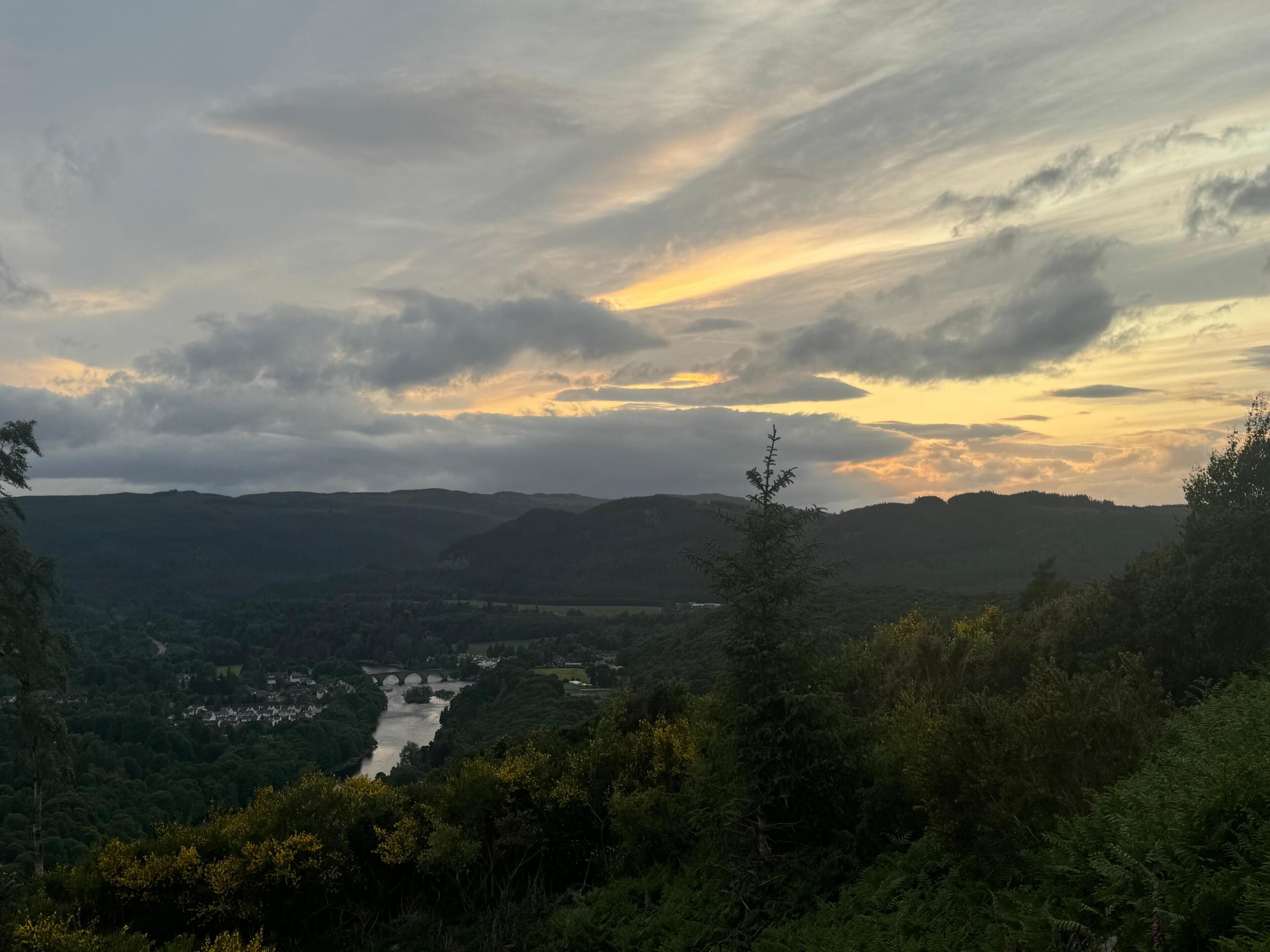 A landscape with a river, hills, and a bridge.